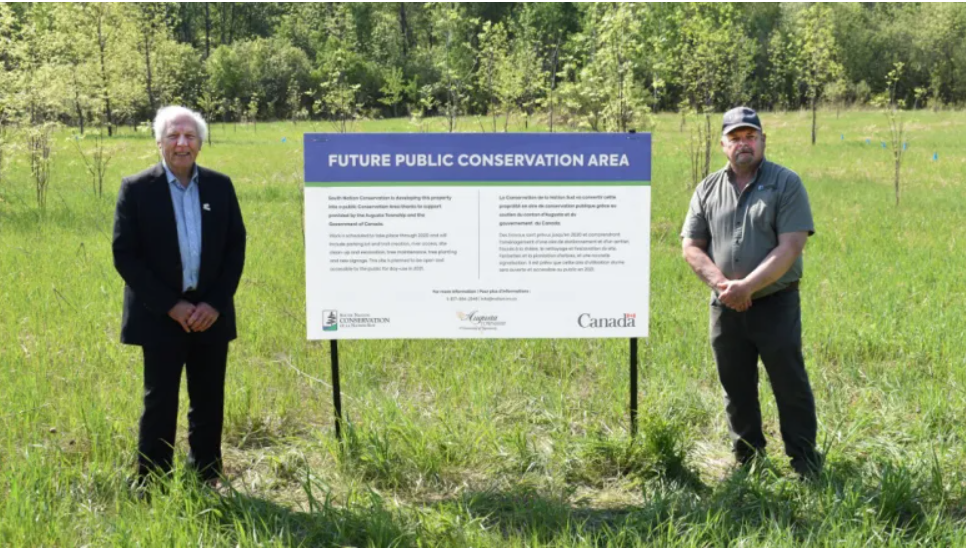 Doug Malanka, Mayor of Augusta Township (pictured left), and Pat Piitz, SNC's Properties Lead (pictured right), stand next to a temporary project sign installed at the new Conservation Area site on McCrea Road